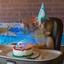 A baby in a high chair with a party hat has a cake on the tray..jpg
